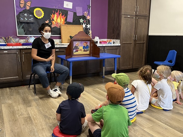 Photo de Lucie Chaudy racontant des histoires avec un Kamishibai à des enfants en camp de vacances d'été