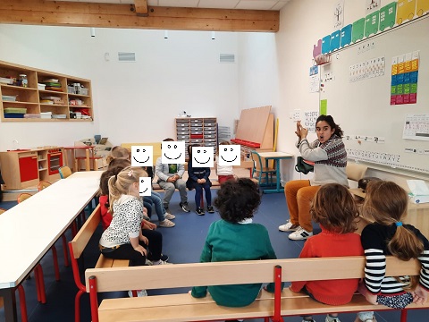 Photo de Lucie Chaudy racontant des histoires traditionnnelles à des élèves attentifs de maternelle