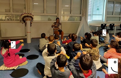 Photo de la conteuse, Lucie Chaudy et d'élèves de maternelle et d'élémentaire en train de chanter des refrains