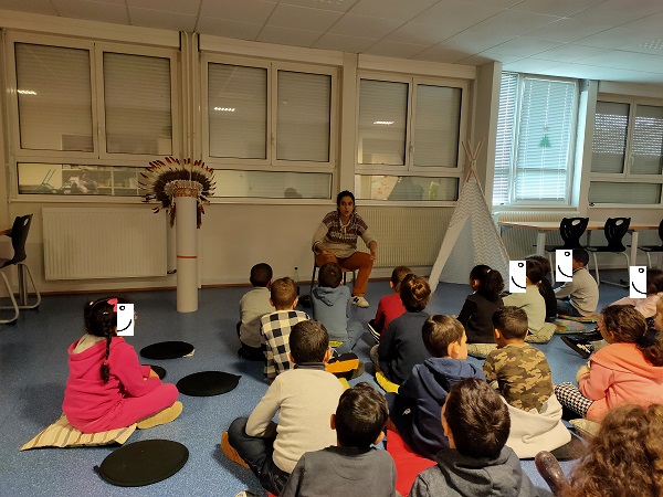 Photo de la conteuse racontant des contes amérindiens devant un groupe d'enfants de CP et de CE1 dans une école élémentaire