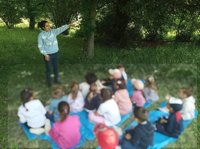 Conteuse qui raconte sous un arbre aux élèves attentifs